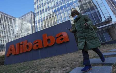 A woman wearing a face mask run past the offices of Chinese e-commerce firm Alibaba in Beijing on Dec. 13, 2021.