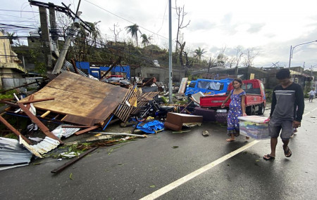 Residents carry what's left of their belongings as they walk past damaged homes due to Typhoon Rai in Surigao city, Surigao del Norte, central Philippines on Friday Dec. 17, 2021.