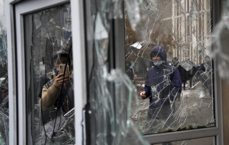 A man takes a photo of windows of a police kiosk damaged by demonstrators during a protest in Almaty, Kazakhstan, Wednesday, Jan. 5, 2022.