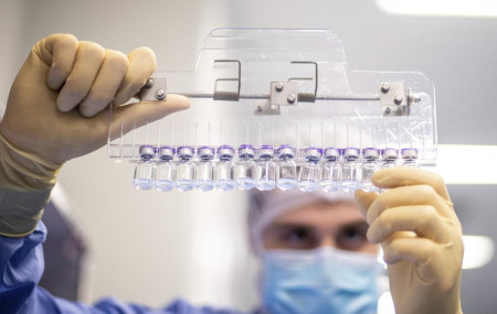 In this photo provided by Pfizer, a technician inspects filled vials of the Pfizer-BioNTech COVID-19 vaccine at the company's facility in Puurs, Belgium in March 2021.