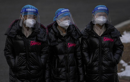 Workers wearing face shields and masks to help protect from the coronavirus head to a hotel used for people to stay during a period of health quarantine Sunday, March 20, 2022, in the Yanqing district of Beijing.