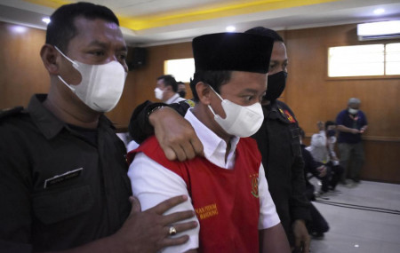 Herry Wirawan, center, the principal of a girls Islamic boarding school accused of raping his students, is escorted by security officers upon arrival for his sentencing hearing at a district court in Bandung, West java, Indonesia, on Feb. 15, 2022.
