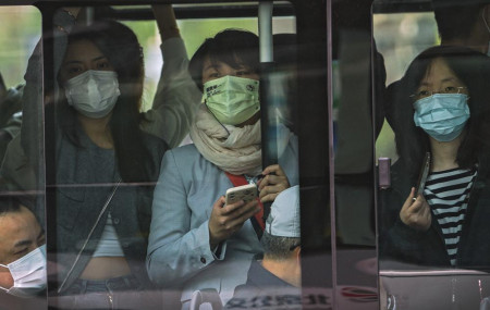 Commuters wearing face masks to help protect from the coronavirus look out from a crowded traveling bus during the morning rush hour, Monday, April 18, 2022, in Beijing.