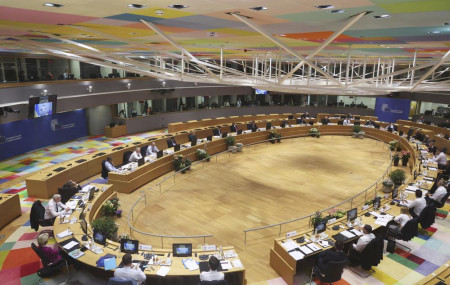 Ukrainian President Volodymyr Zelenskyy is seen on a screen, left, as addresses from Kyiv during an extraordinary meeting of EU leaders to discuss Ukraine, energy and food security at the Europa building in Brussels, Monday, May 30, 2022.