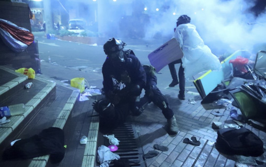 A policeman in riot gear detains a protester outside of Hong Kong Polytechnic University as police storm the campus in Hong Kong, early Monday, Nov. 18, 2019.
