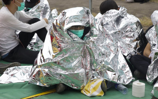 An injured youth sits under a space blanket at a casualty evacuation point near Hong Kong Polytechnic University in Hong Kong, Tuesday, Nov. 19, 2019.