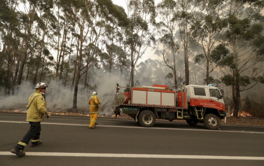 A firefighting crew battles a fire near Burrill Lake, Australia, Sunday, Jan. 5, 2020. Milder temperatures Sunday brought hope of a respite from wildfires that have ravaged three Australian states, destroying almost 2,000 homes.