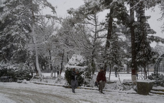 In this Sunday, Jan. 12, 2020, photo, people walk on a road during heavy snow fall in Quetta, capital of Pakistan's southwestern Baluchistan province.