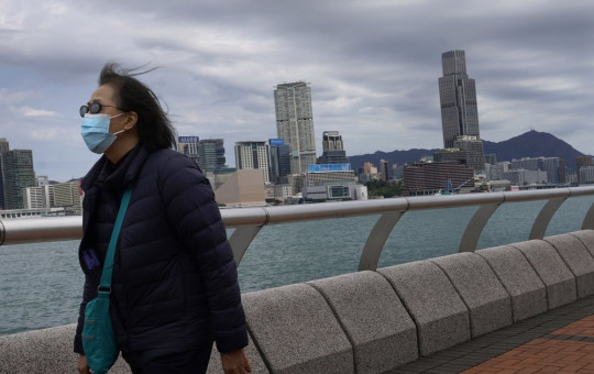 A woman wearing a face mask walks at the waterfront against the Victoria Habour in Hong Kong Sunday, Feb. 16, 2020. COVID-19 viral illness has sickened tens of thousands of people in China since December.