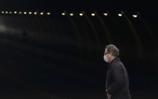 A man wears a mask while crossing in front of the Stockton Street Tunnel in San Francisco, Sunday, March 29, 2020.