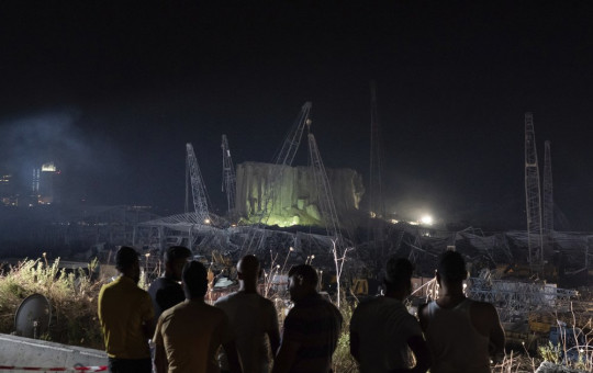 People look at the scene of Tuesday's explosion that hit the seaport of Beirut, Lebanon, Friday, Aug. 7, 2020.
