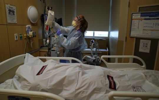 Registered nurse Nikki Hollinger cleans up a room as a body of a COVID-19 victim lies in a body bag labeled with stickers at Providence Holy Cross Medical Center in the Mission Hills section of Los Angeles, Saturday.