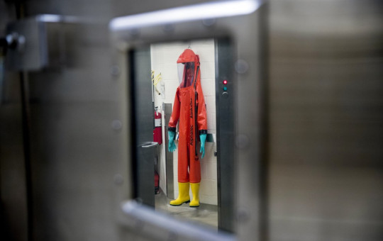 In this March 19, 2020, file photo, a biosafety protective suit for handling viral diseases are hung up in a biosafety level 4 training facility at U.S. Army Medical Research and Development Command at Fort Detrick in Frederick, Maryland.