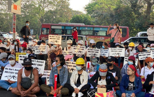 Anti-coup protesters hold signs that read