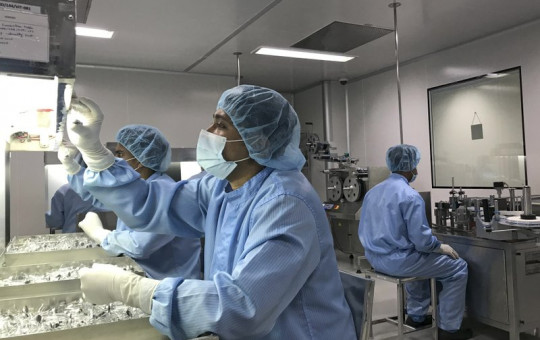 Production personnel perform a visual inspection of filled vaccine vials inside the Incepta plant on the outskirts of Dhaka in Bangladesh Saturday Feb. 13, 2021.