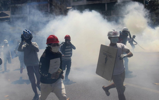 Anti-coup protesters run away from tear gas launched by security forces in Yangon, Myanmar, Monday, March 1, 2021.