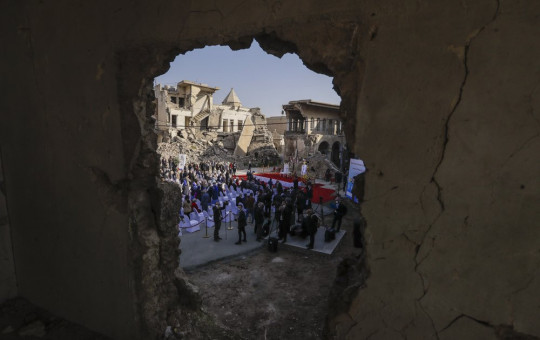 Surrounded by shells of destroyed buildings people arrive to join Pope Francis who will pray for the victims of war at Hosh al-Bieaa Church Square, in Mosul, Iraq, once the de-facto capital of IS, Sunday, March 7, 2021.