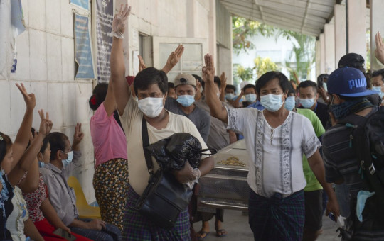 Relatives and friends of Khat Aung Phyo, a boy who was killed by bullet on March 14, raise a three-finger salute, a symbol of resistance, as his body is moved out from a mortuary in Yangon, Myanmar, Monday, March 15, 2021.