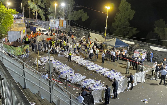 Israeli security officials and rescuers stand around the bodies of victims who died during a Lag Ba'Omer celebrations at Mt. Meron in northern Israel, Friday, April 30, 2021.