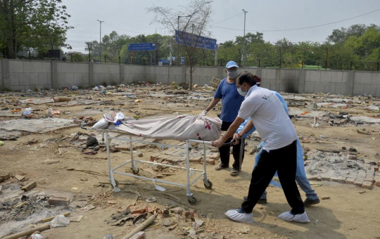 Body of a COVID-19 victim is wheeled in a ground that has been converted into a crematorium in New Delhi, India, Saturday, May 1, 2021.