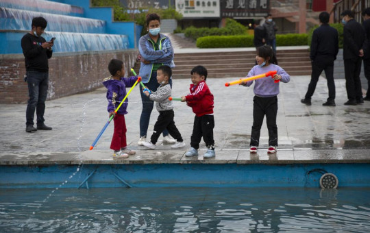 Children play with water toys at a public square in Aksu in western China's Xinjiang Uyghur Autonomous Region, Tuesday, April 20, 2021.