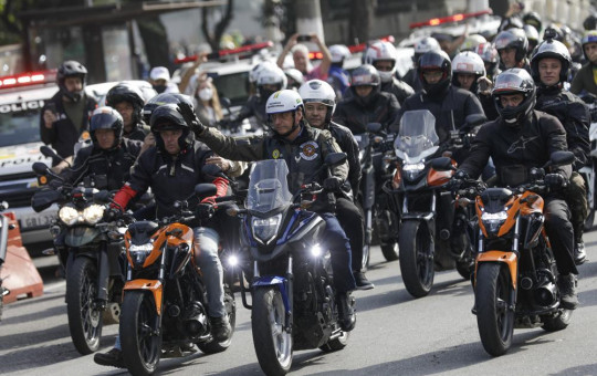 Brazil's President Jair Bolsonaro, center, waves as he leads a caravan of motorcycle enthusiasts following him through the streets of the city, in a show of support for Bolsonaro, in Sao Paulo, Brazil, Saturday, June 12, 2021.