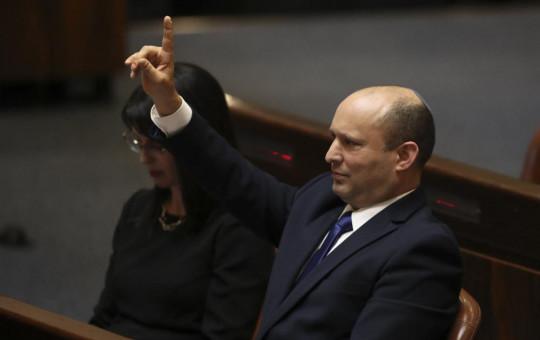 Israel's new prime minister Naftali Bennett raises his hand during a Knesset session in Jerusalem Sunday, June 13, 2021.