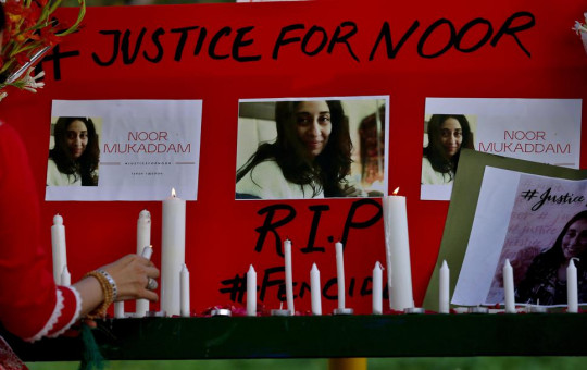 A women's rights activist places a candle beside a poster with the pictures of Noor Mukadam, who was recently beheaded, during a candle light vigil to pay tribute to Noor and other domestic violence victims, in Islamabad.