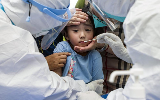 A child reacts to a throat swab during mass testing for COVID-19 in Wuhan in central China's Hubei province Tuesday, Aug. 3, 2021.