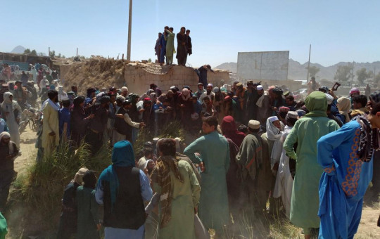 Taliban fighters and Afghans gather around the body of a member of the security forces who was killed, inside the city of Farah, capital of Farah province, southwest Afghanistan, Wednesday, Aug. 11, 2021.