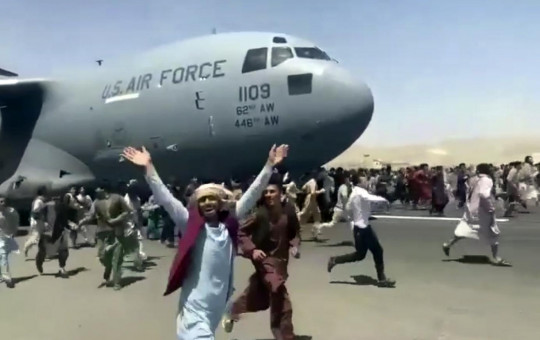 Hundreds of people run alongside a U.S. Air Force C-17 transport plane as it moves down a runway of the international airport, in Kabul, Afghanistan, Monday, Aug.16. 2021.