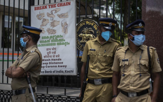 Police personnel wearing masks guard outside the Reserve Bank of India during a protest against the federal government's plan to privatize government assets in Kochi, Kerala state, India, Tuesday, Aug.31, 2021.