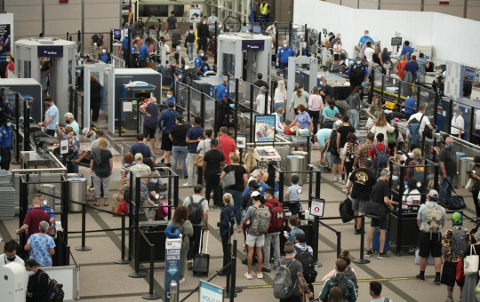 Travelers wear face coverings in the line for the north security checkpoint in the main terminal of Denver International Airport Tuesday, Aug. 24, 2021, in Denver.