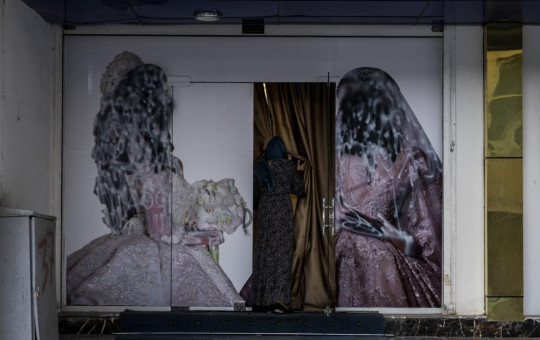 An Afghan woman enters a beauty salon in Kabul, Afghanistan, Saturday, Sept. 11, 2021. Since the Taliban gained control of Kabul, several images depicting women outside beauty salons have been removed or covered up.