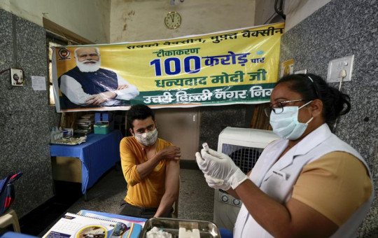 A health worker inoculates a man next to a banner thanking Prime Minister Narendra Modi for 1 billion doses of COVID-19 vaccine at a government hospital in New Delhi, India, Thursday, Oct. 21, 2021.