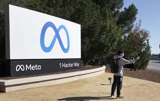 A Facebook employee take a selfie in front the company's new name and logo outside its headquarters in Menlo Park, Calif., Thursday, Oct. 28, 2021, after announcing that it is changing its name to Meta Platforms Inc.