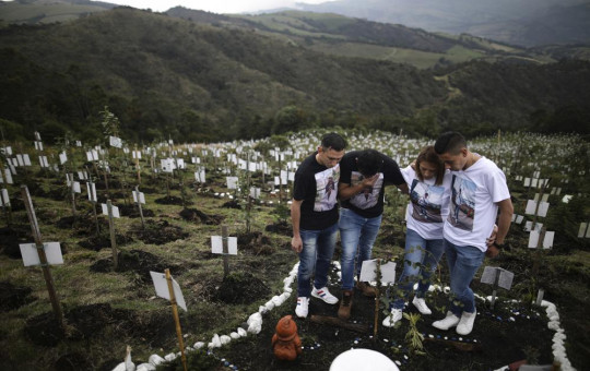 Relatives of Luis Enrique Rodriguez, who died of COVID-19, visit where he was buried on a hill at the El Pajonal de Cogua Natural Reserve, in Cogua, north of Bogota, Colombia, Monday, Oct. 25, 2021.
