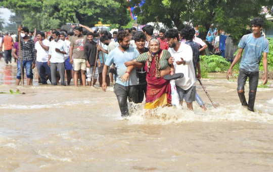 People wade through a flooded street in Nellore, in the southern Indian state of Andhra Pradesh, Saturday, Nov. 20, 2021.