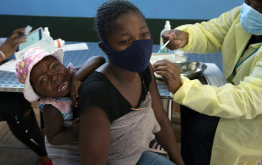 A baby cries as her mother receives her Pfizer vaccine against COVID-19, in Diepsloot Township near Johannesburg Thursday, Oct. 21, 2021.