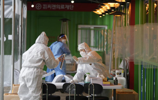 Medical workers wearing protective gear prepare to take samples at a temporary screening clinic for the coronavirus in Seoul, South Korea, Wednesday, Dec. 29, 2021.