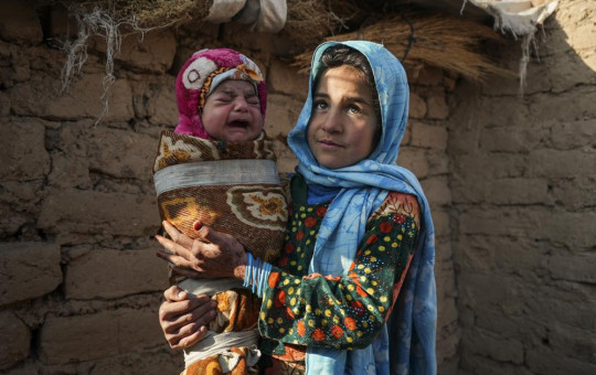 Qandi Gul holds her brother outside their home housing those displaced by war and drought near Herat. Gul’s father sold her into marriage without telling his wife, taking a down-payment so he could feed his family of five kids..