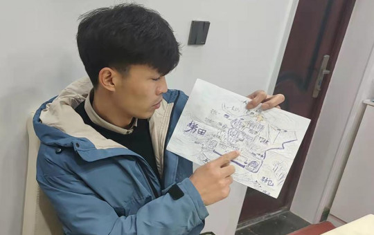 Li Jingwei points to a detail a map he drew from memory of his childhood village as he sits in Lankao in central China's Henan Province, Wednesday, Jan. 5, 2022.