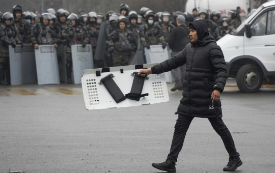 A demonstrator carries a police shield in front of police line during a protest in Almaty, Kazakhstan, Wednesday, Jan. 5, 2022.