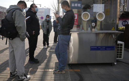 Workers and residents stand near a nuclei test station in Beijing, China, Tuesday, Jan. 18, 2022.
