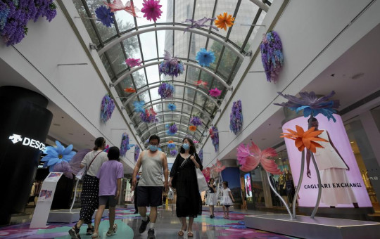 Residents wearing face masks walk through the reopening shopping mall decorated with colorful flowers after being closed due to COVID-19 restrictions in Beijing, Sunday, May 29, 2022.