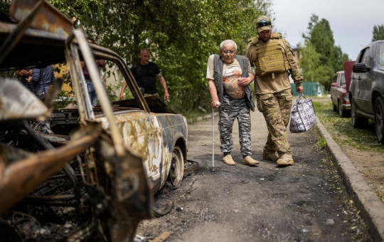 A volunteer helps a man leaving his home in a building damaged by an overnight missile strike, in Sloviansk, Ukraine, Tuesday, May 31, 2022.