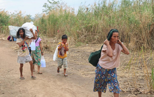 FILE - Displaced people from Myanmar carry donated lunch boxes to their tents along the Thai side of the Moei River in Mae Sot, Thailand on Feb. 5, 2022.