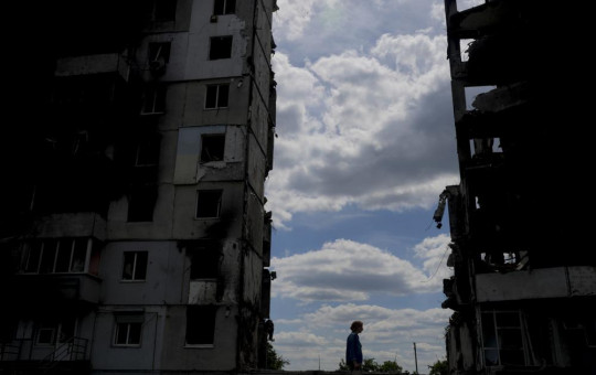 A woman walks in front of buildings destroyed during attacks in Borodyanka, on the outskirts of Kyiv, Ukraine, Saturday, June 4, 2022.