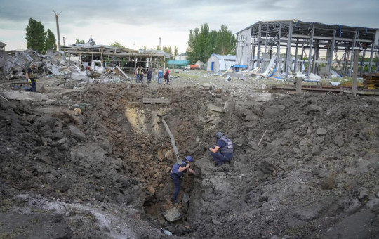 Police members inspect a crater caused by a Russian rocket attack in Pokrovsk, Donetsk region, Ukraine, Wednesday, June 15, 2022.