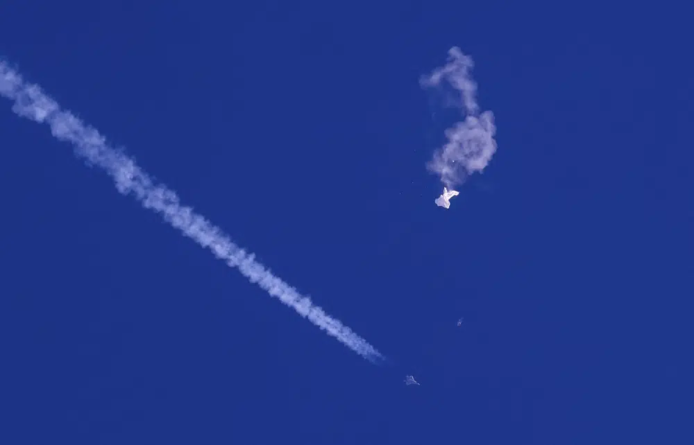 In this photo provided by Chad Fish, the remnants of a large balloon drift above the Atlantic Ocean, just off the coast of South Carolina, with a fighter jet and its contrail seen below it, Saturday, Feb. 4, 2023. AP/RSS Photo